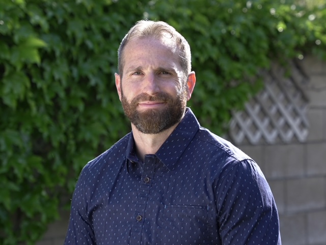 Outdoor headshot against a leafy backdrop